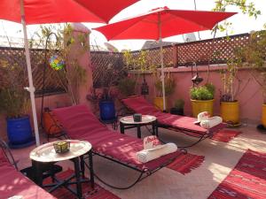 une terrasse avec des chaises rouges, des tables et un parasol dans l'établissement Arabian Riad Marrakech, à Marrakech