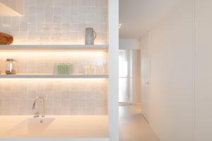 a kitchen with a sink and a white counter at Een designappartement met zijdelings zicht op zee in Ostend