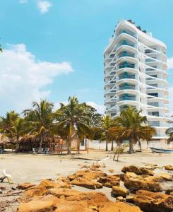 ein Gebäude am Strand mit Palmen und Felsen in der Unterkunft Magico Apartamento Frente al Mar 3 Habitaciones FB73 in Coveñas