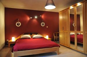1 dormitorio con 1 cama con pared roja en Gite Au Phil du Temps, en Érezée