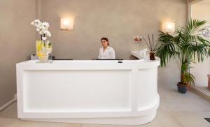 a woman sitting at a reception desk in a room at Hotel Cecina Beach in Marina di Cecina