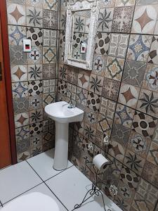 Hospedaria e Hostel da Déia في أورو بريتو: حمام مع حوض ومرآة وبلاط