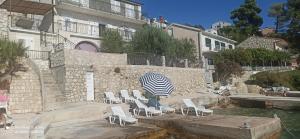 a group of chairs and an umbrella next to the water at Apartment on the beach in Lokva Rogoznica