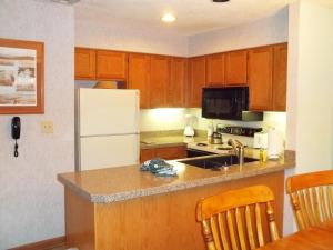 a kitchen with wooden cabinets and a white refrigerator at Fairways of the Mountain, a VRI resort in Lake Lure