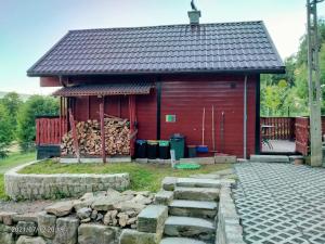 un bâtiment rouge avec une pile de bûches devant lui dans l'établissement Kuligowka Szklarska Poreba, à Szklarska Poręba