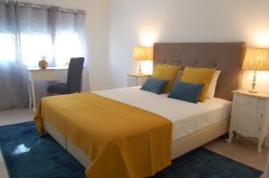 a bedroom with a large bed with yellow and blue pillows at Atlantic Town 2 - Free Parking in Ponta Delgada
