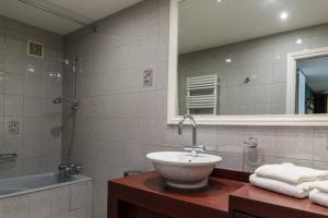 ein Badezimmer mit einem Waschbecken, einer Badewanne und einem Spiegel in der Unterkunft Clos de Marie Appartement de Charme + Park Couvert in Font Romeu Odeillo Via