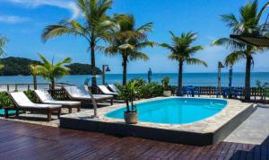 a swimming pool with palm trees and the ocean at Pousada Coração da Ilha do Mel in Ilha do Mel