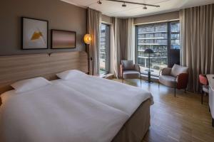 a hotel room with a large white bed and chairs at Scandic CPH Strandpark in Copenhagen