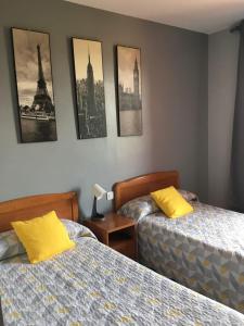 a bedroom with two beds and pictures on the wall at Hostal La Concha in Somo