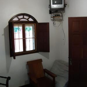 Zimmer mit einem Fenster, einem Stuhl und einem TV in der Unterkunft Residencial Gaivotas 40m da praia Nova vicosa in Nova Viçosa