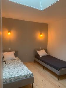 une chambre avec deux lits et deux lumières sur le mur dans l'établissement L’Estable du Pin, à Le Pin
