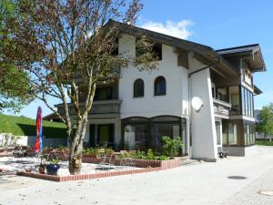 ein Gebäude mit Stühlen und einem Baum davor in der Unterkunft Gästehaus Friedlich in Schönau am Königssee