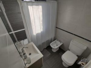 a white bathroom with a toilet and a sink at Frente al mar charlone in Mar del Plata