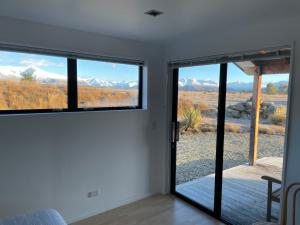 Cette chambre dispose de portes coulissantes en verre offrant une vue sur les montagnes. dans l'établissement Mt Barker, à Wanaka