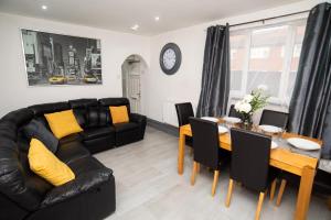 a living room with a black leather couch and a table at South Cheshire House in Wistaston