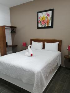 Un dormitorio con una cama blanca con un cisne. en Hotel Maria Maria en Bacalar