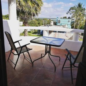 a glass table and two chairs on a balcony at Hotel Maria Maria in Bacalar