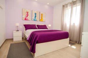Dormitorio blanco con cama morada y ventana en La Huerta de Manuel, en Tejina