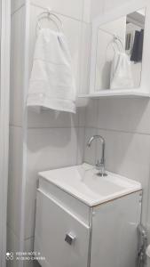 a white bathroom with a sink and a mirror at Pousada Quarto família ar, frigobar,wi fi in Aparecida