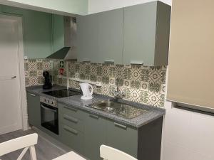 a kitchen with green cabinets and a sink at CASA do CAMINHO in Praia da Vitória