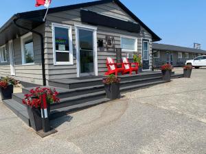 une maison avec 2 chaises rouges sur la terrasse couverte dans l'établissement Oreland Motel, à Flin Flon