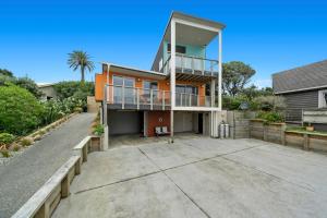 an orange house with a balcony and a driveway at Rippling Waves Lookout - Raumati South Home in Raumati South