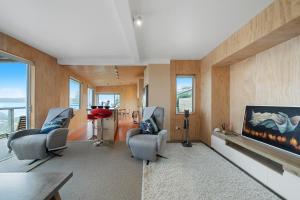 a living room with two chairs and a fireplace at Rippling Waves Lookout - Raumati South Home in Raumati South
