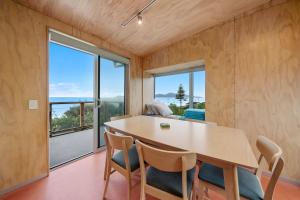 a dining room with a table and chairs and a large window at Rippling Waves Lookout - Raumati South Home in Raumati South