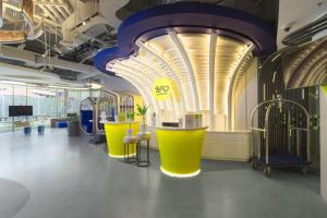 a room with yellow and blue tables and a ceiling at YELLO Hotel Kuta Beachwalk Bali in Kuta