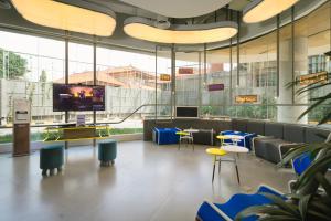 a lobby with a tv and tables and chairs at YELLO Hotel Kuta Beachwalk Bali in Kuta