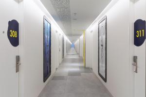 a corridor with white walls and a long hallway with doors at YELLO Hotel Kuta Beachwalk Bali in Kuta
