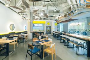 a restaurant with tables and chairs and a cafeteria at YELLO Hotel Kuta Beachwalk Bali in Kuta