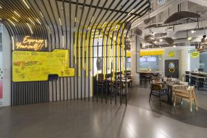 a restaurant with tables and chairs and a yellow sign at YELLO Hotel Kuta Beachwalk Bali in Kuta