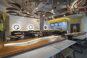 a restaurant with a large wooden counter and tables and chairs at YELLO Hotel Kuta Beachwalk Bali in Kuta