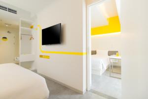 a bedroom with a bed and a tv on a wall at YELLO Hotel Kuta Beachwalk Bali in Kuta