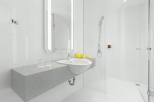 a white bathroom with a sink and a shower at YELLO Hotel Kuta Beachwalk Bali in Kuta