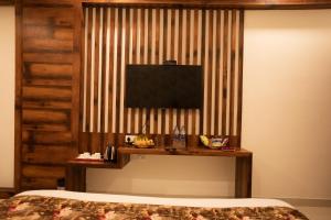 1 dormitorio con 1 cama y TV en la pared en Hotel Bhairav Bagh with Swimming Pool, en Udaipur