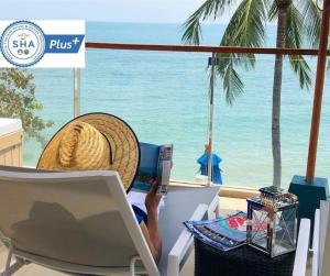 une personne assise sur une chaise en utilisant un ordinateur portable sur la plage dans l'établissement Royal Beach Boutique Resort & Spa Koh Samui - SHA Extra Plus, à Lamai