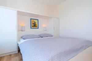 een witte slaapkamer met een bed en 2 kussens bij The Blueview Appartements Novigrad in Novigrad Istria