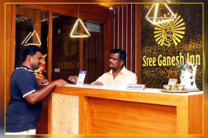 two men standing at the counter of a restaurant at Sree Ganesh Inn in Palni