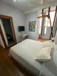 een slaapkamer met een wit bed en een spiegel bij Casa Urriola B&B in Valparaíso