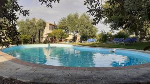 a large swimming pool with blue chairs in a yard at Poggio Mario in Saturnia