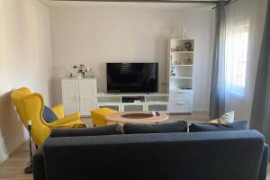 uma sala de estar com um sofá azul e cadeiras amarelas em Cozy family house em Ventspils