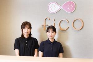 two young people standing in front of a sign with the word flex at fico HIJI in Hiji