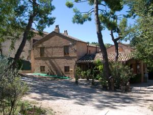 a large stone house with trees in front of it at B&B La Cappellania in Montegiorgio