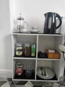 a white shelf with dishes and a coffee pot on it at Number 6 in St Austell