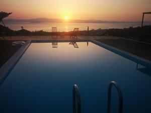 a swimming pool with a sunset in the background at Villa Freebird - VIP Wedding & Bachelor Events in Pefkochori