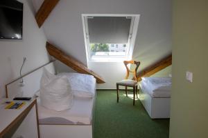 Habitación pequeña con 2 camas y silla en Gästehaus Reckahn der Rochow Akademie, en Reckahn