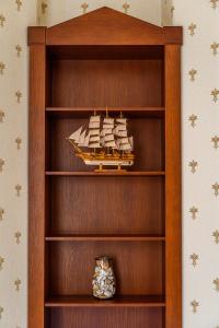 Una estantería de madera con un modelo de barco encima. en Fregata, en Liepāja